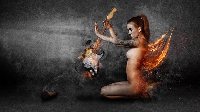 Nahá žena s ohnivými krídlami drží v rukách elektrickú gitaru.jpg